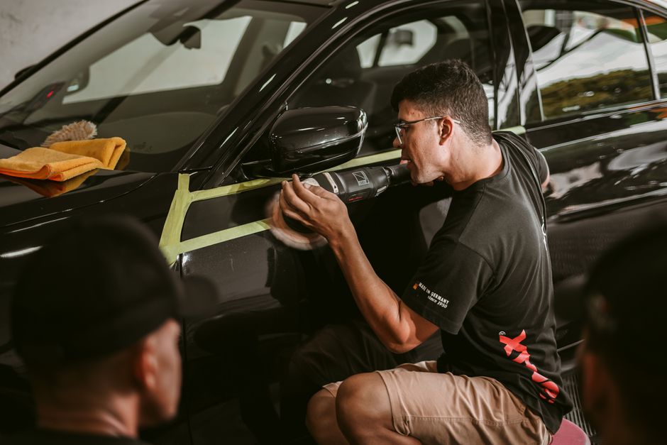 A man meticulously polishes a car, showcasing precision in an automotive workshop.